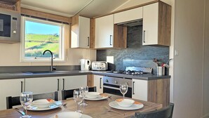 Een moderne keuken met een eethoek, voorzien van een fornuis, magnetron en uitzicht op het groen.