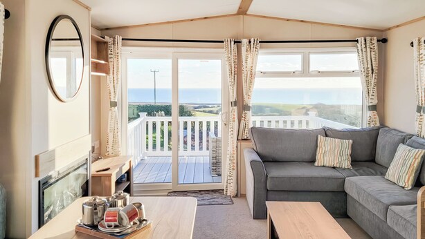 A cozy room with a sofa, a wooden table, and a view of a balcony with a white fence. - 2 bedroom accommodation in Dorchester (Dorchester)