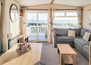 A cozy room with a sofa, a wooden table, and a view of a balcony with a white fence.