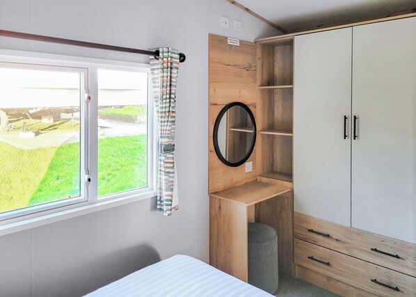 A bedroom with a window, a bed, a wardrobe, and a mirror.