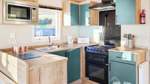 A compact kitchen with a microwave, stove, oven, and sink. - 2 bedroom accommodation in Dorchester (Dorchester)
