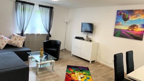 Ein modernes Wohnzimmer mit einer Couch, einem Couchtisch, einem Fernseher und einem bunten Teppich.