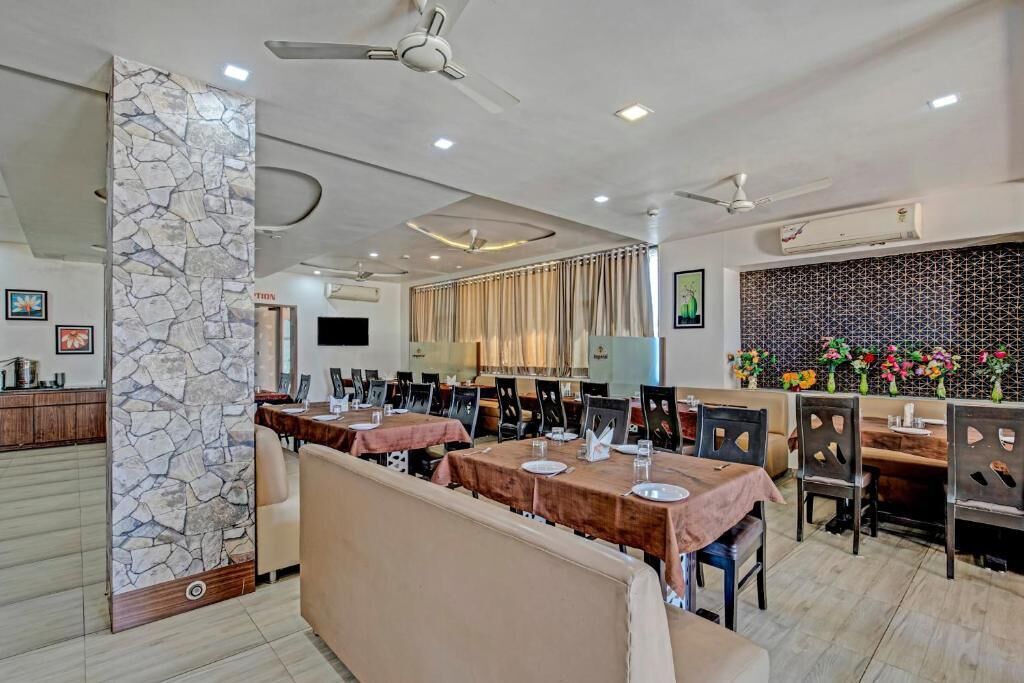 A restaurant with multiple tables, ceiling fans, and a stone accent wall.