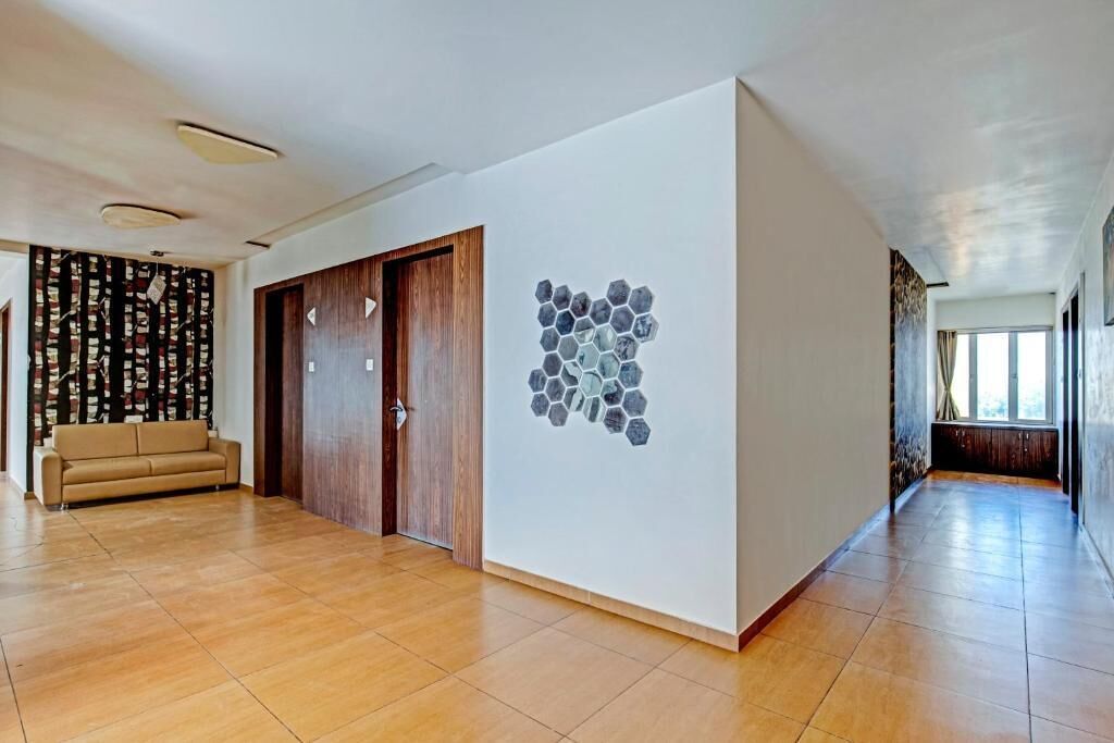 Um corredor espaçoso com piso de madeira, um sofá bege e uma porta de madeira.