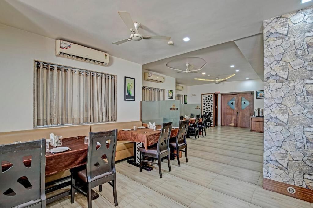 A restaurant with multiple tables and chairs, ceiling fans, and stone wall accents.