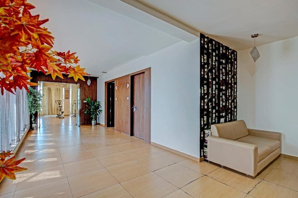A spacious hallway with a beige sofa, wooden doors, and a decorative wall panel.