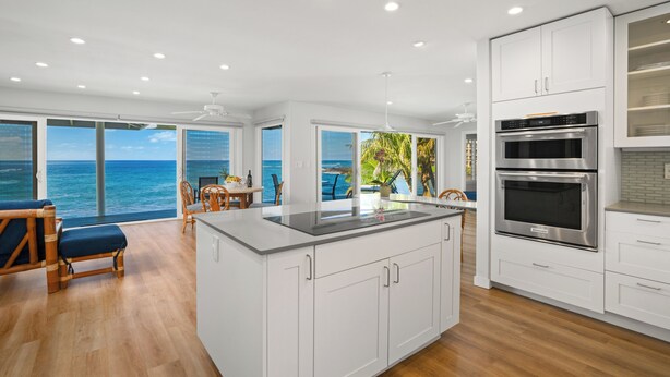 A modern kitchen with white cabinets, stainless steel appliances, and a large island. - Ho'ona Beach House by Alekona Kauai: 3BR Oceanfront Poipu Paradise (Koloa)