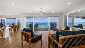 A spacious living area with a view of the ocean, featuring wooden furniture and a ceiling fan. - Ho'ona Beach House by Alekona Kauai: 3BR Oceanfront Poipu Paradise (Koloa)