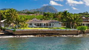A beachfront property with a house featuring a covered patio, a swimming pool, and a view of the ocean and mountains. - Ho'ona Beach House by Alekona Kauai: 3BR Oceanfront Poipu Paradise (Koloa)