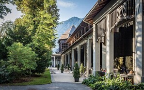 A building with a covered walkway, columns, and a mountain in the background.