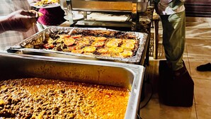 A buffet with various food items, including a large tray of what appears to be a tomato-based dish and another tray with sliced tomatoes. - Room-wadi Rum Main Road Visitor Center (Wadi Rum)
