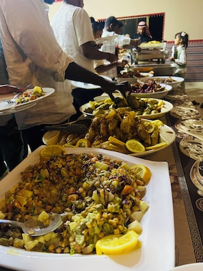 A buffet with various dishes, including a large salad and a dish with chickpeas. - Room-wadi Rum Main Road Visitor Center (Wadi Rum)