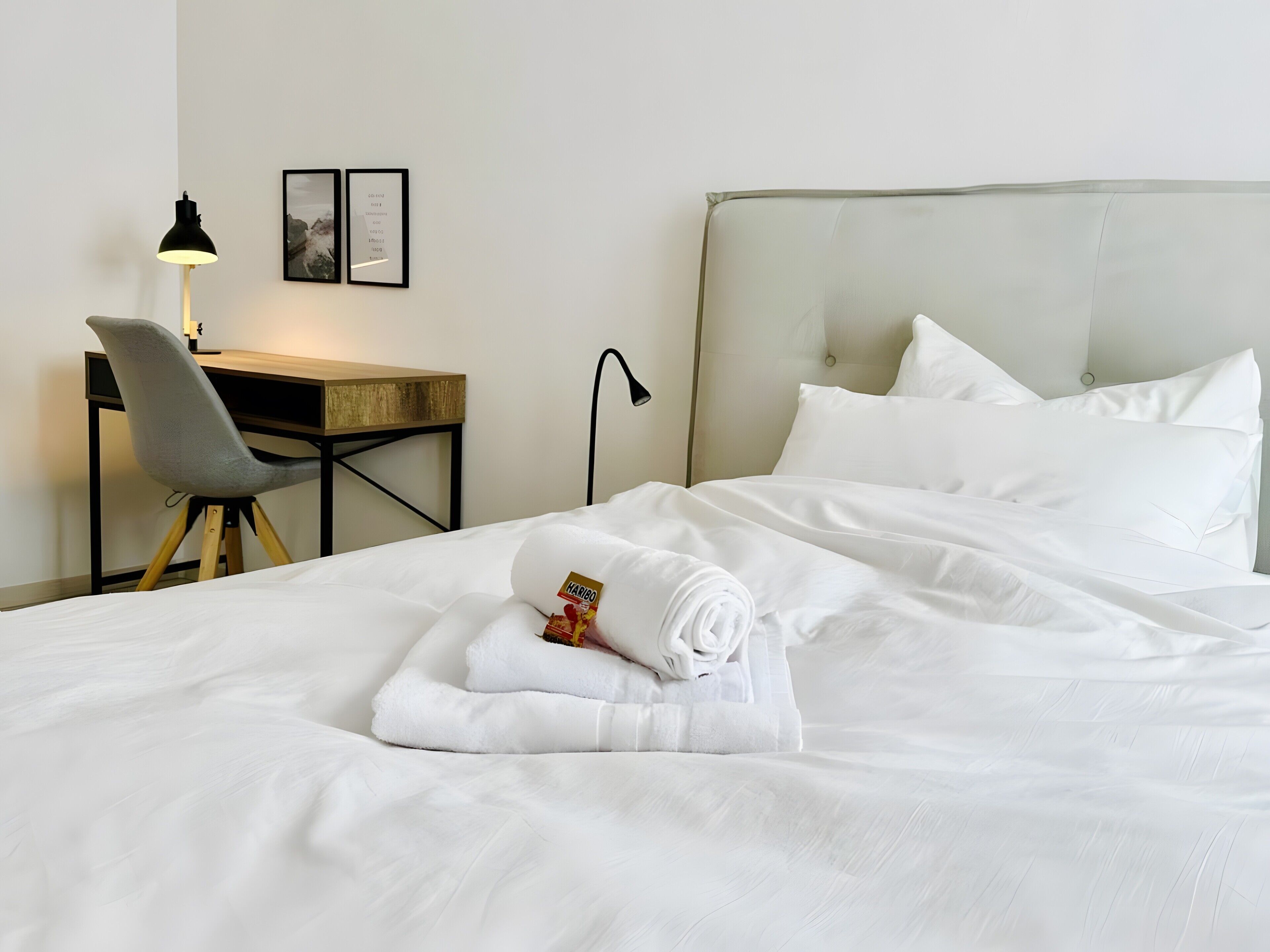 Una habitación de hotel con una cama, un escritorio, una silla, una lámpara y un cuadro en la pared.