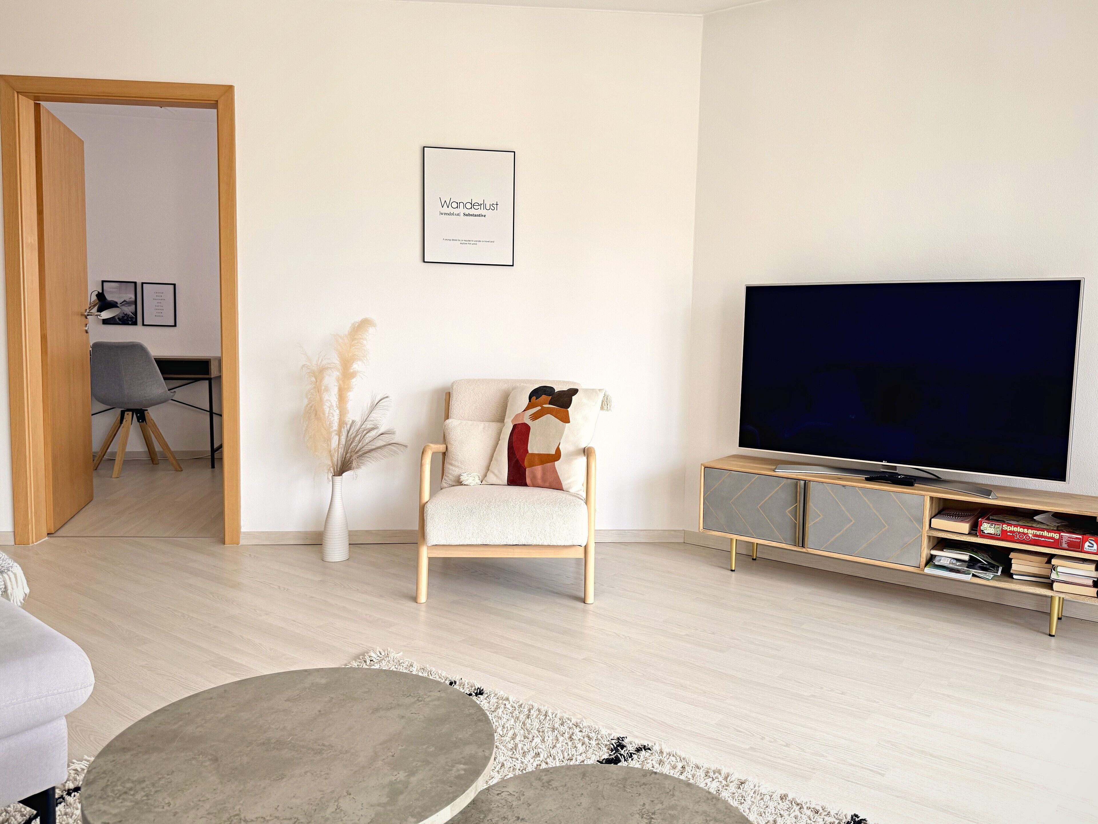 Un salon moderne comprenant un canapé, un fauteuil, un téléviseur, une bibliothèque et un tableau encadré accroché au mur.