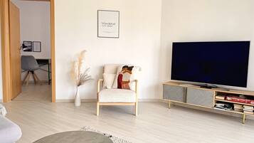Un salon moderne comprenant un canapé, un fauteuil, un téléviseur, une bibliothèque et un tableau encadré accroché au mur.