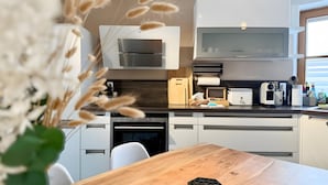 Een moderne keuken met een houten tafel, een koffieapparaat en een vaatwasser.