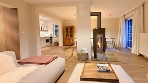 Ein modernes Wohnzimmer mit Sofa, Hocker und Kamin.