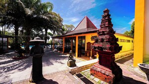 A temple with a red roof and a statue in front. - Tripletree Ciptaningati Culture Hotel (Batu)