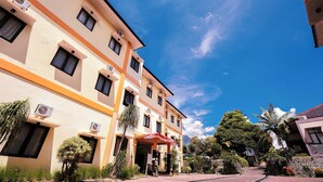 A multi-story building with air conditioning units, a covered entrance, and a landscaped garden with various plants and a statue. - Tripletree Ciptaningati Culture Hotel (Batu)