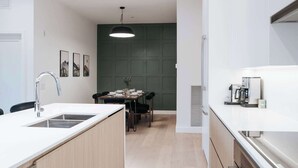 Et moderne køkken med indbygget komfur, vask og spiseplads med bord dækket til to.