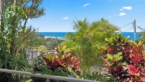 Un balcon agrémenté de plantes tropicales et offrant une vue sur l’océan.