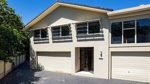 Un bâtiment à deux étages doté d’un garage, d’une porte d’entrée et d’un petit porche.
