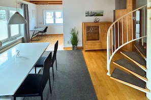 A modern interior with a dining table, chairs, a staircase, and a wooden cabinet. - Holiday home in Bestwig with ski-storage (Bestwig)