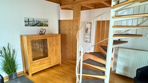 A wooden staircase with a handrail, a wooden cabinet with glass doors, and a framed picture on the wall.