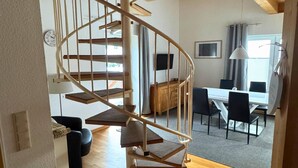 A modern interior with a spiral staircase, a dining area, and a living space.