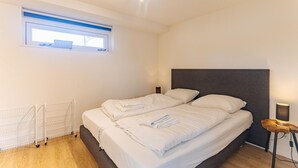 A bedroom with a bed, a window, a radiator, and a bedside lamp. - Coastal Family Escape with Enclosed Garden (Renesse)