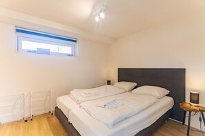 Un dormitorio con cama, ventana, radiador y lámpara de noche.