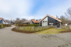 A residential area with modern houses, paved pathways, and a wooden fence. - Coastal Family Escape with Enclosed Garden (Renesse)