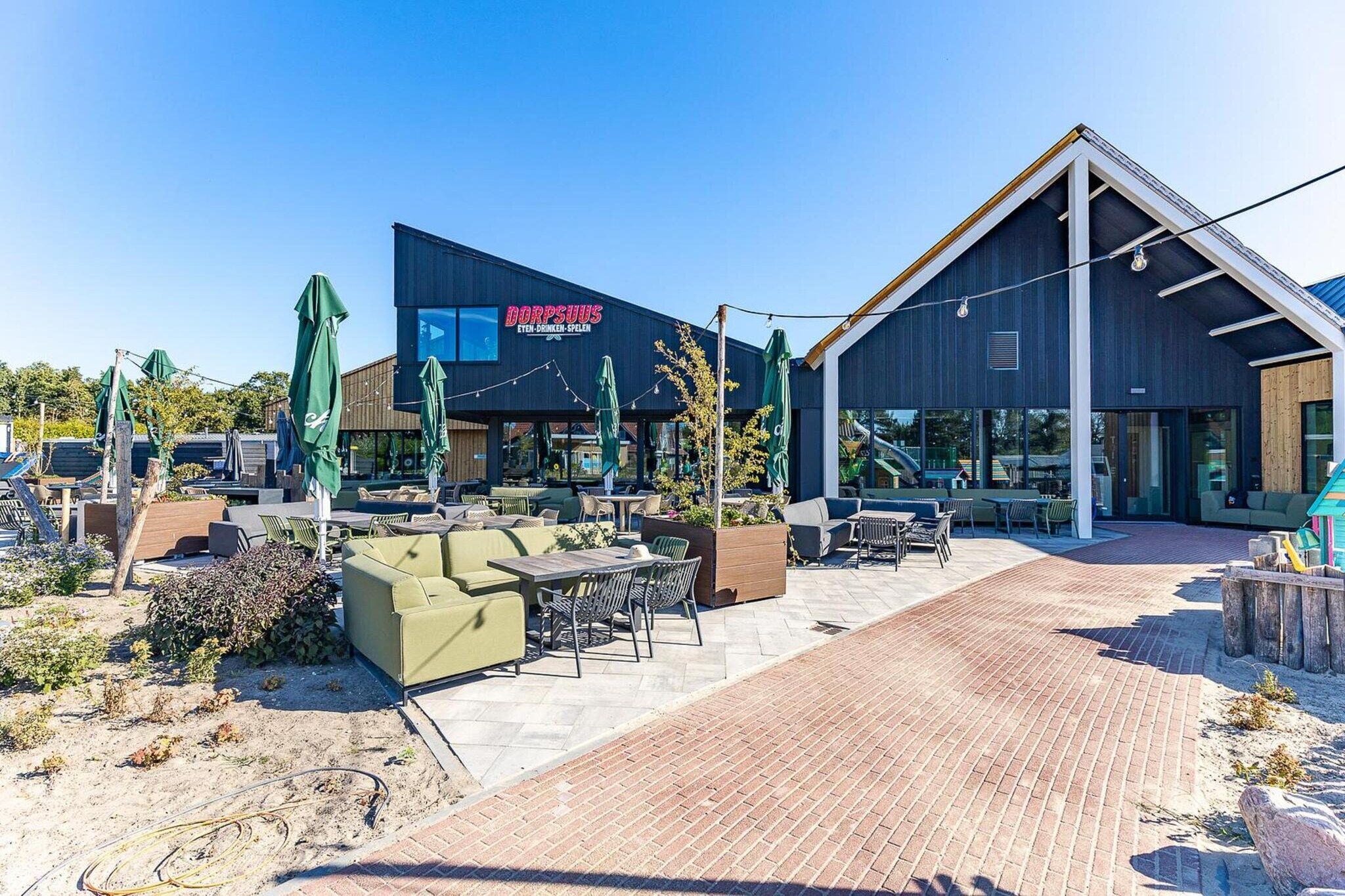 Un espace extérieur moderne aménagé avec des tables et des chaises, un bâtiment avec une enseigne et un ciel dégagé.