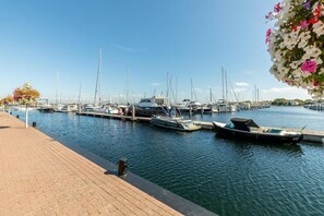 Ein Yachthafen mit mehreren vertäuten Booten, einer Holzpromenade und einem klaren Himmel.