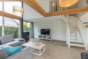 Un salon moderne comprenant un canapé, une table basse, un téléviseur et un escalier menant à un espace extérieur.