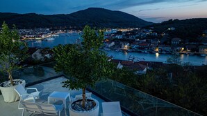Eine Terrasse mit Sitzgelegenheiten und Blick auf einen Hafen im Abenddämmerung.