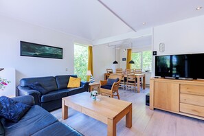 Ein modernes Wohnzimmer mit einer schwarzen Ledersofa, einem Holztisch und einem Fernseher auf einer Holzkommode.
