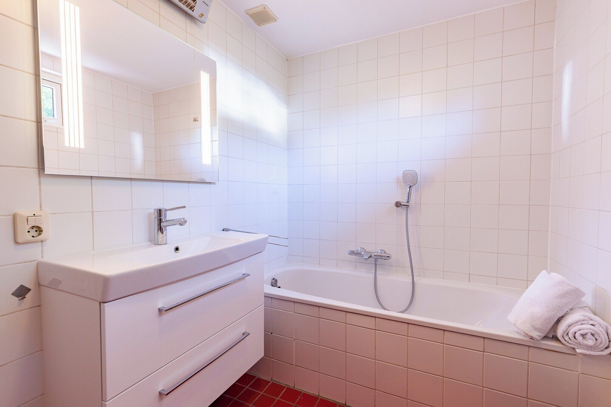 Un bagno con lavandino bianco, specchio e vasca.