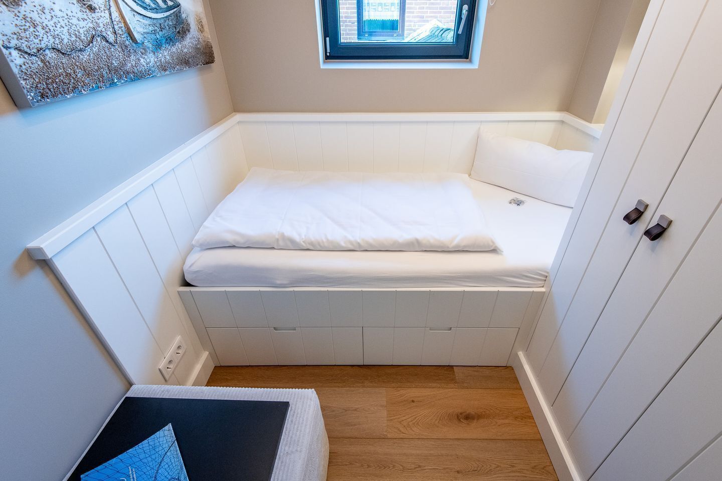 A compact room with a bed, a small window, and a door.