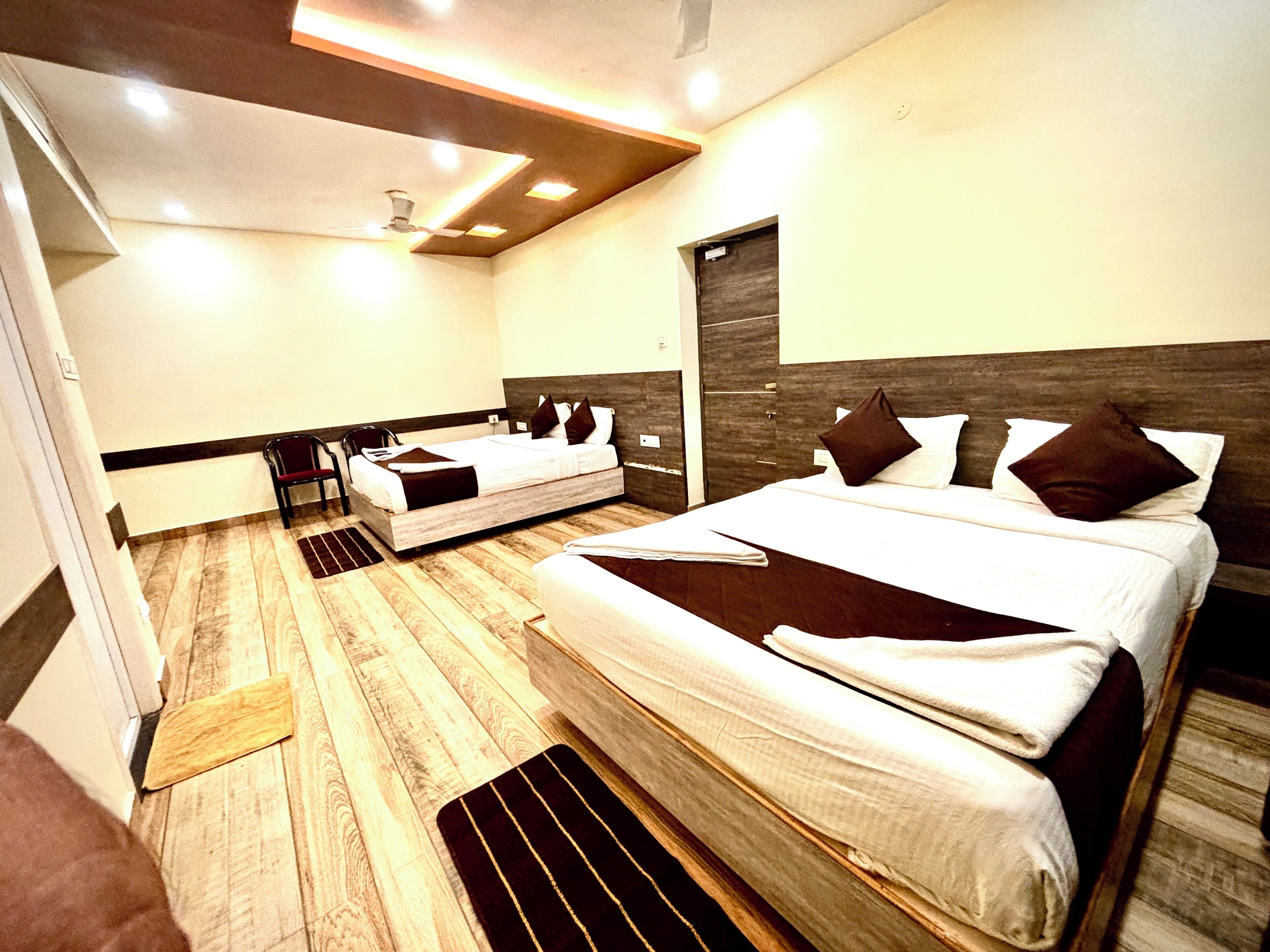 Een moderne hotelkamer met een groot bed, een kleiner bed, een bureau en een stoel.