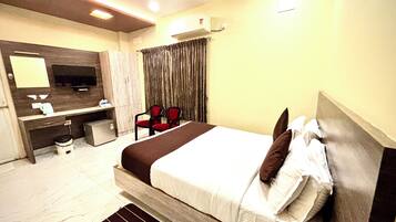 Habitación de hotel con cama, escritorio, silla, televisión y aire acondicionado.
