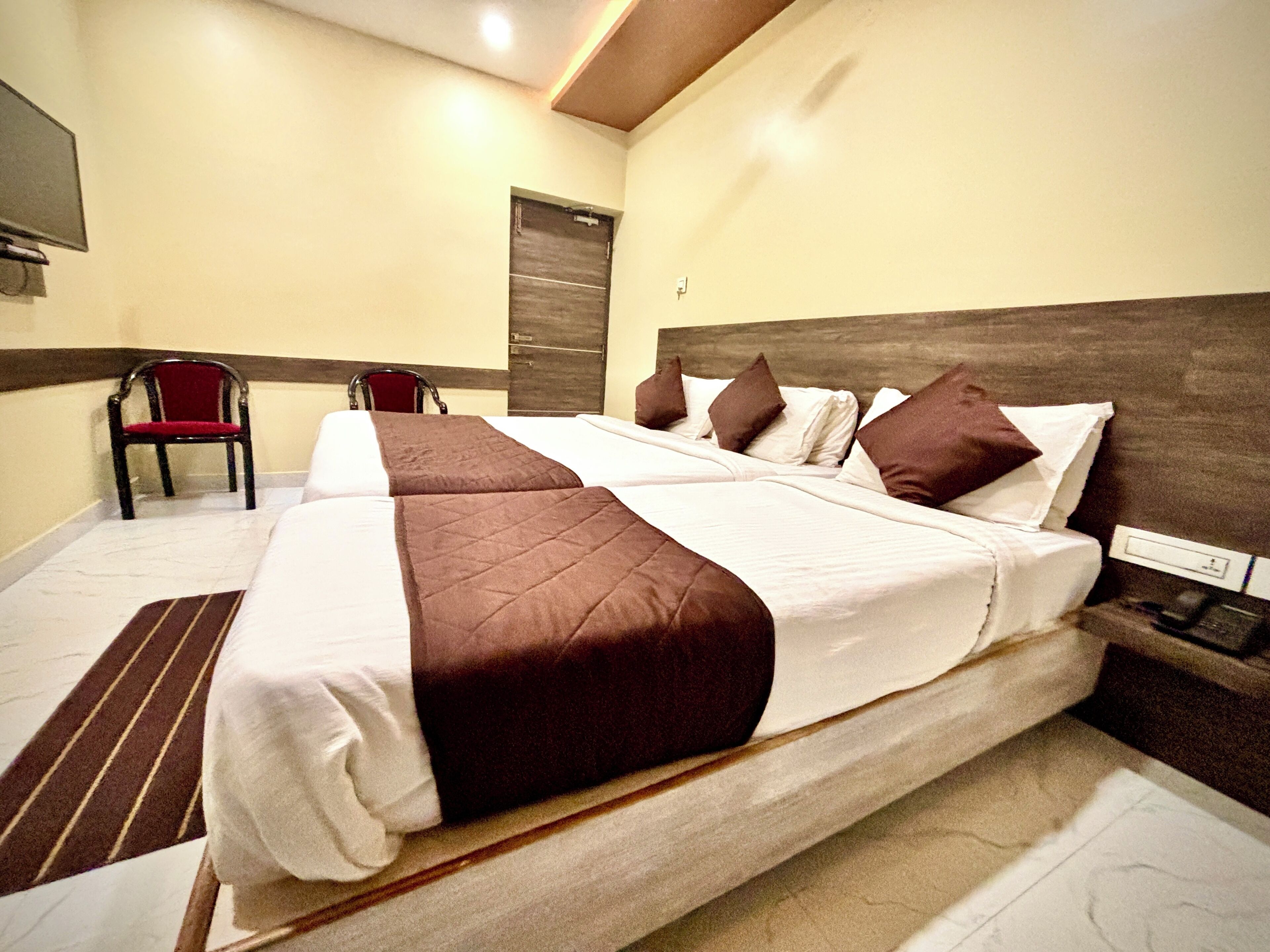 A hotel room with a large bed, a chair, and a wooden headboard.