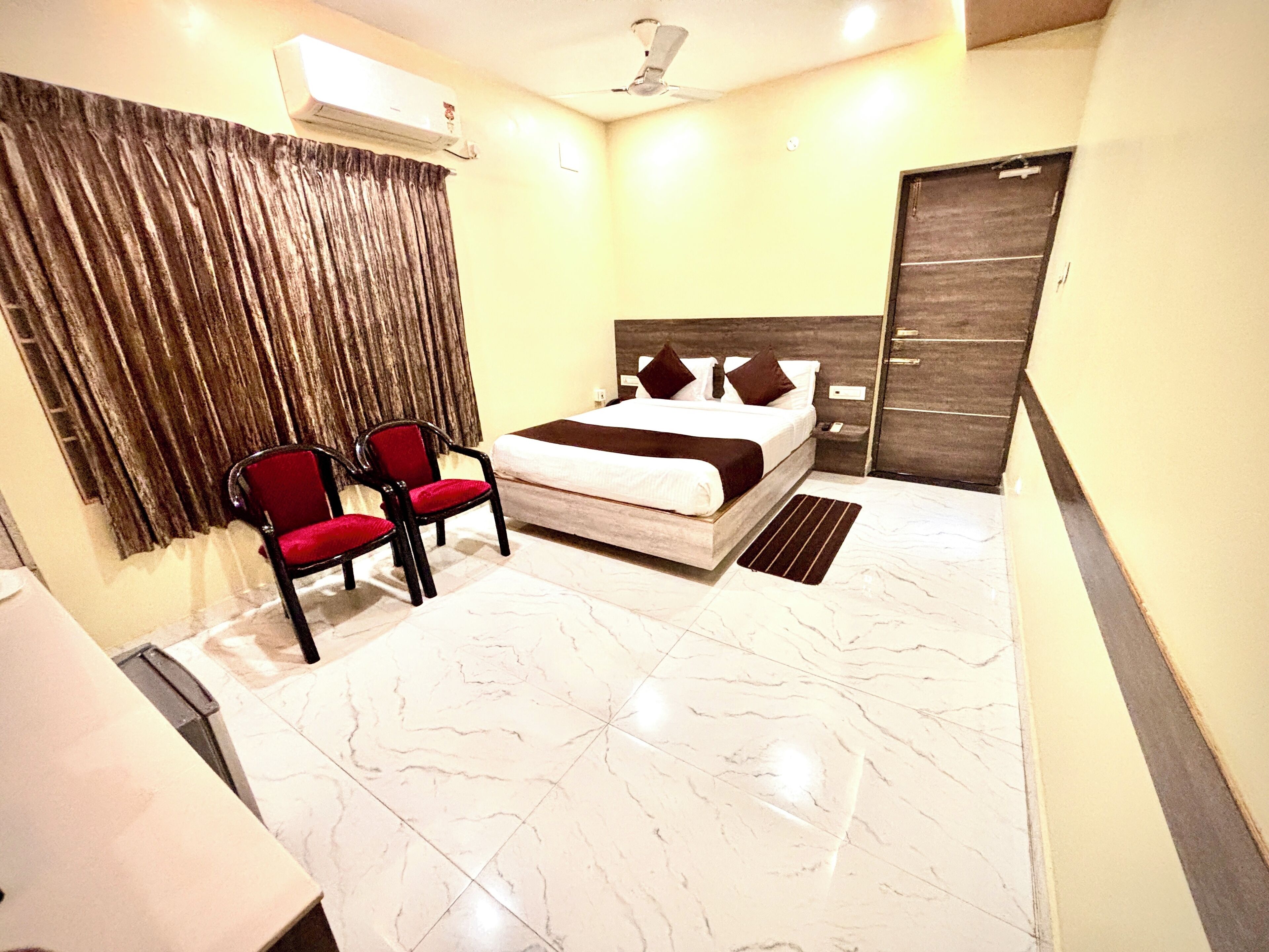 A hotel room with a bed, a chair, a desk, and a wardrobe.