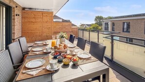 Un balcon avec une table préparée pour le petit-déjeuner, comprenant des croissants, des fruits et des boissons.