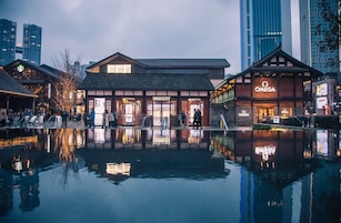 Un edificio frente al agua con un estilo arquitectónico tradicional, que cuenta con tiendas de Breguet y Omega.