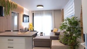 En moderne stue med sofa, spisebord og et køkkenområde.