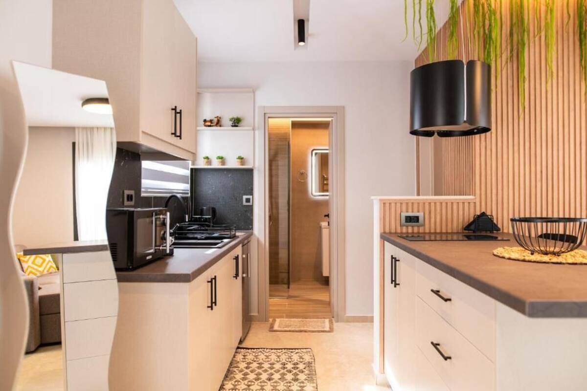 Une cuisine moderne dotée d’un îlot central, d’appareils électroménagers intégrés et d’un mur d’accent en bois.