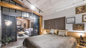 A modern bedroom with a large bed, wooden beams, a desk, and a view into the living area. - Boutique Hotel Casa Verdi (Veliko Tarnovo)