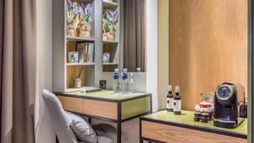 A modern hotel room with a desk, a chair, a bookshelf, and a coffee machine.