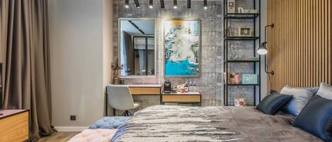 Un dormitorio con una cama grande, un escritorio, una silla, un armario y un espejo.